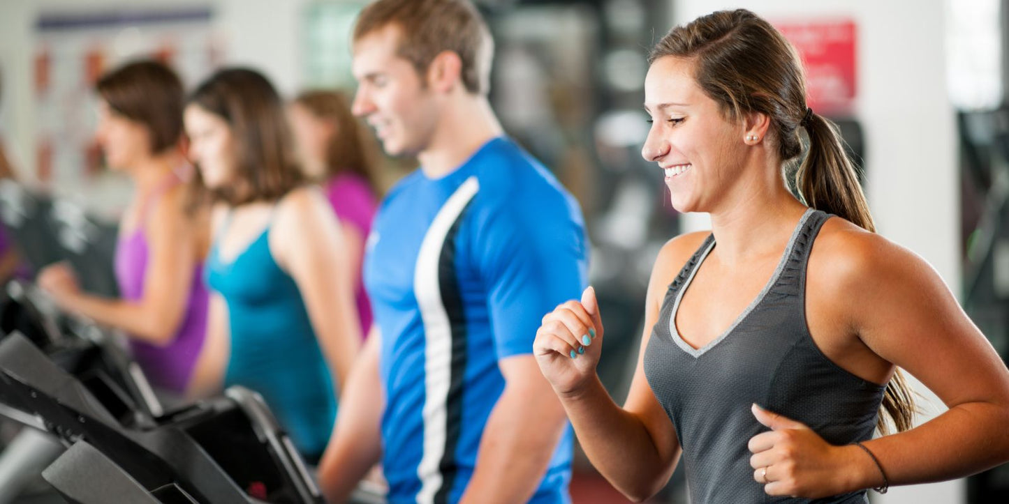 A diverse group of individuals exercising on treadmills in a gym setting, focused on their fitness routines.